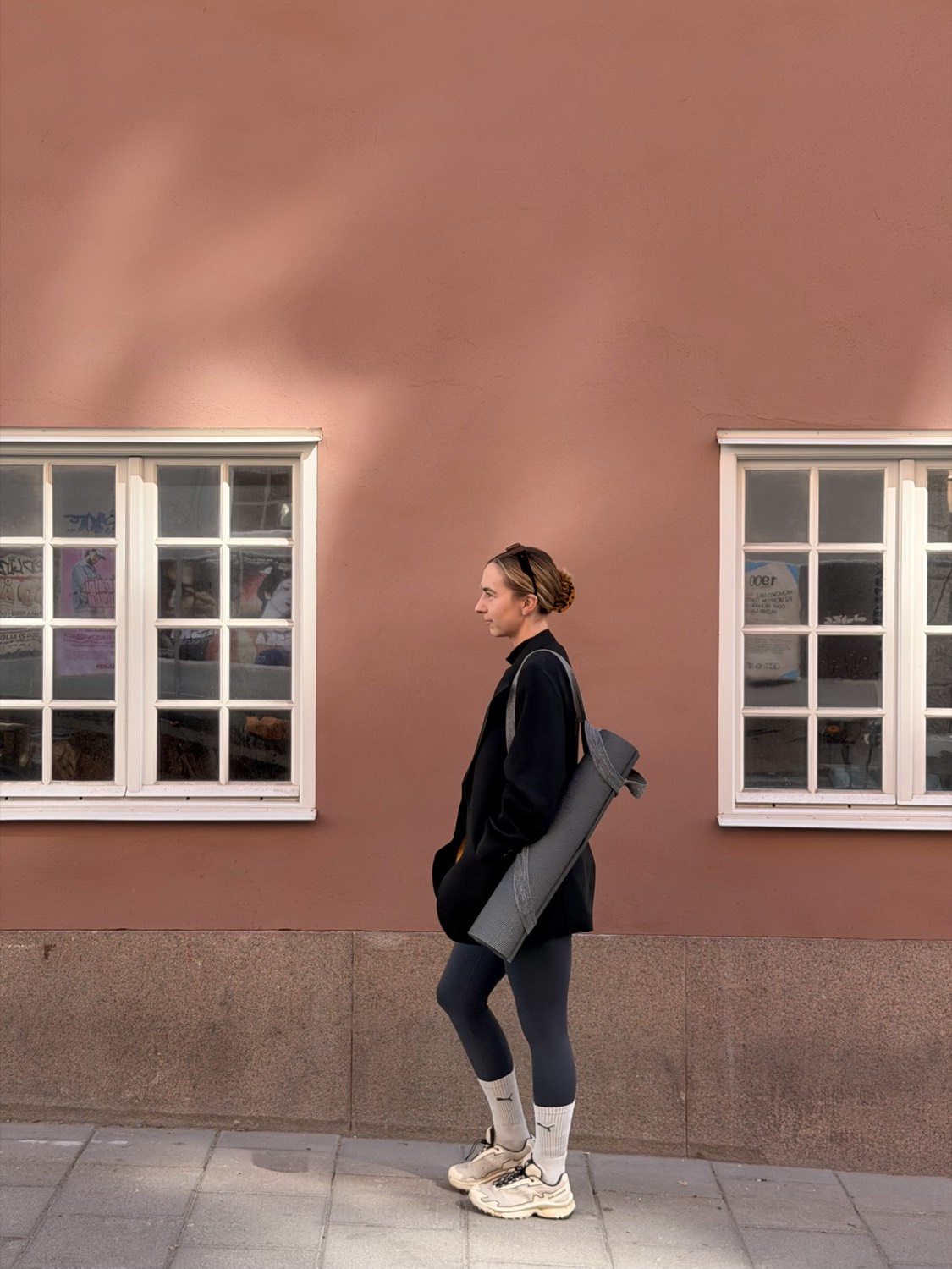 Camilla, a certified yoga teacher, against a sandstone wall in Stockholm